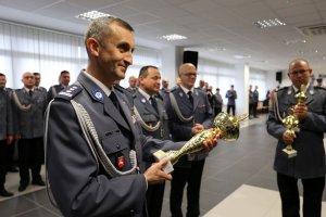 Komendant Wojewódzki Policji w Lublinie trzyma w ręku puchar dla zwycięzców. W drugim planie kadra kierownicza.