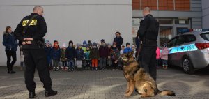 Dzieci z przedszkola z wizytą w KPP Radzyń Podlaski. Na zdjęciu dzieci i przewodnik z policyjnym psem.