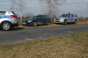dwa radiowozy a pomiędzy nimi zatrzymany po pościgu pojazd marki Volkswagen