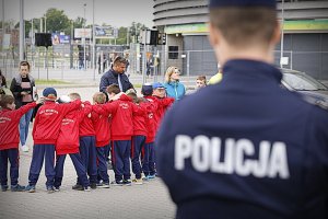 Policjant w tle dzieci robią sobie grupowe zdjęcie.