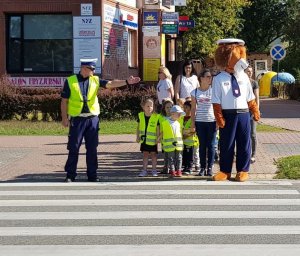 fot. Policjant pokazuje dzieciom sposób przechodzenia przez jezdnię