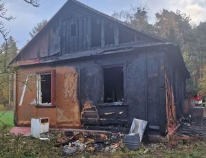 Spalony dom przy którym idzie strażak